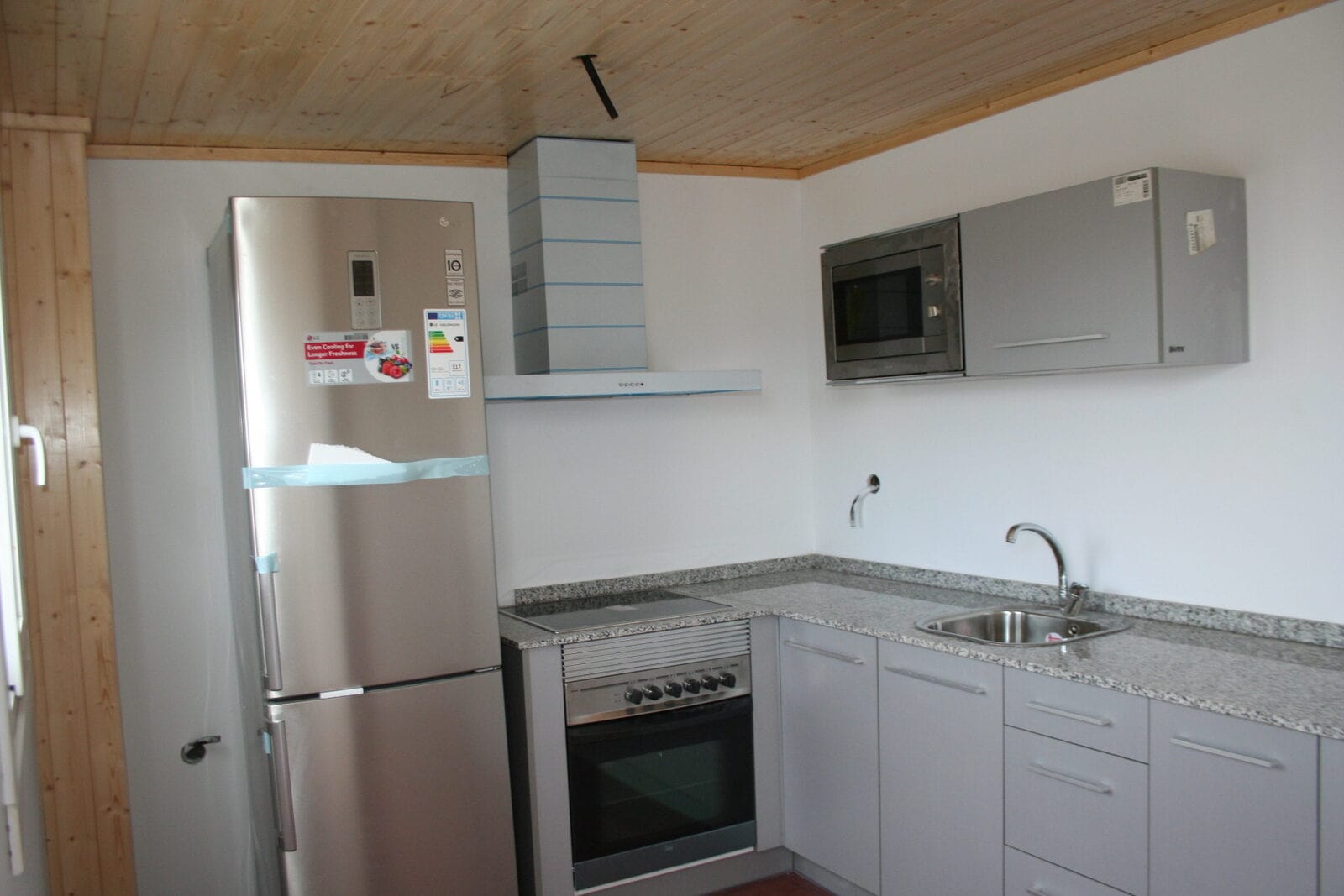 Interior de la cocina terminada del modulo habitable en Almenara Playa: techo de madera, encimera de granito y electrodomesticos instalados